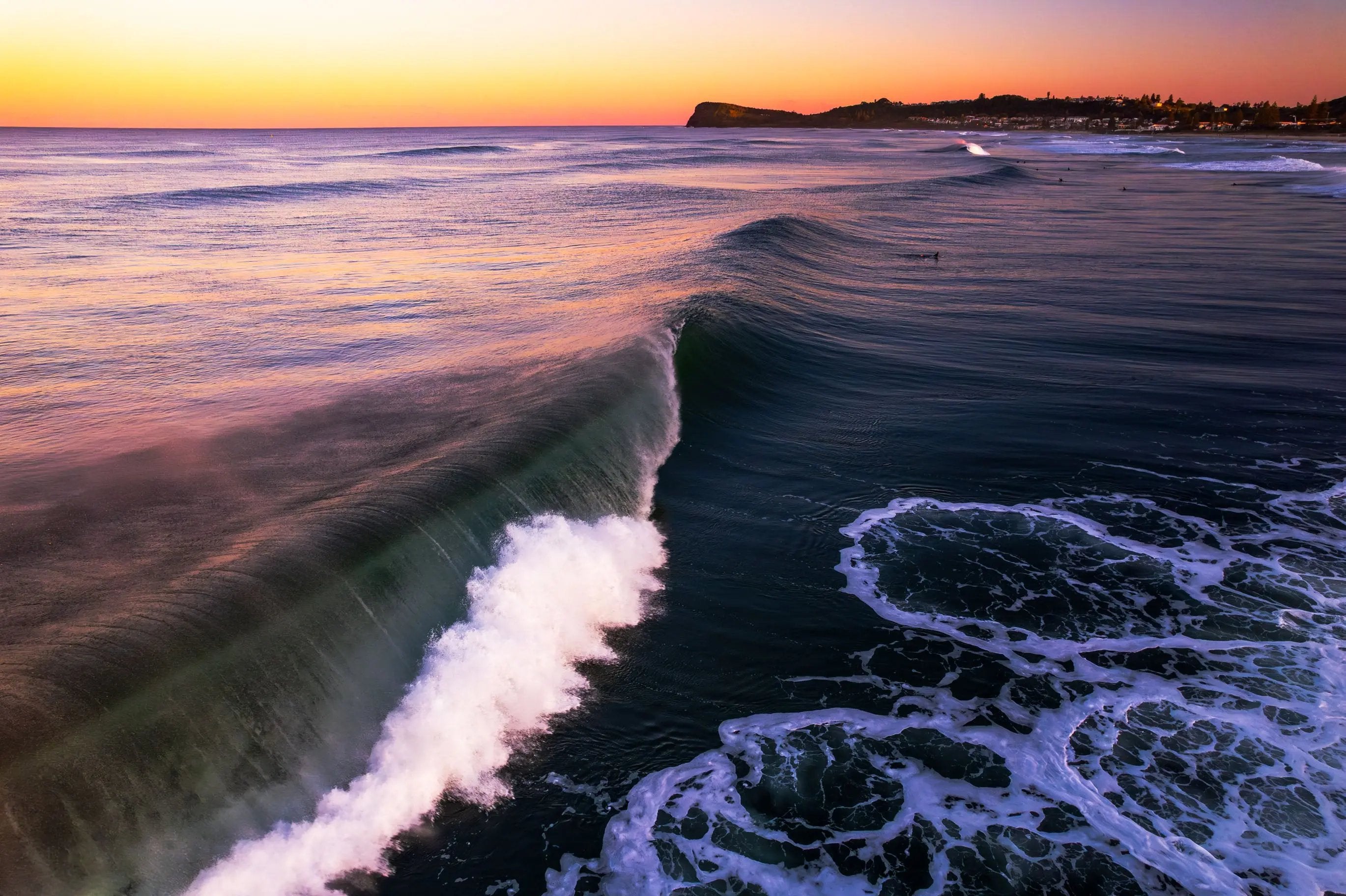 Wave crashing on a beach with a sunset sky