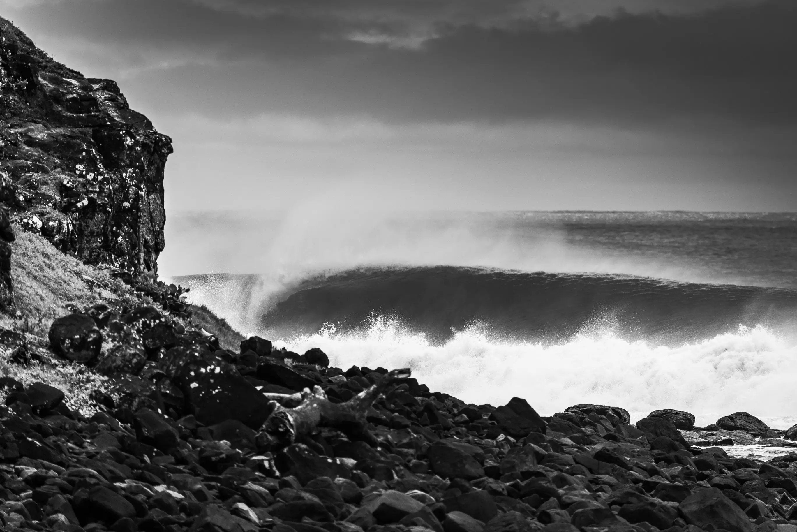 Black and white photo of a rocky coastline with waves crashing against the shore.