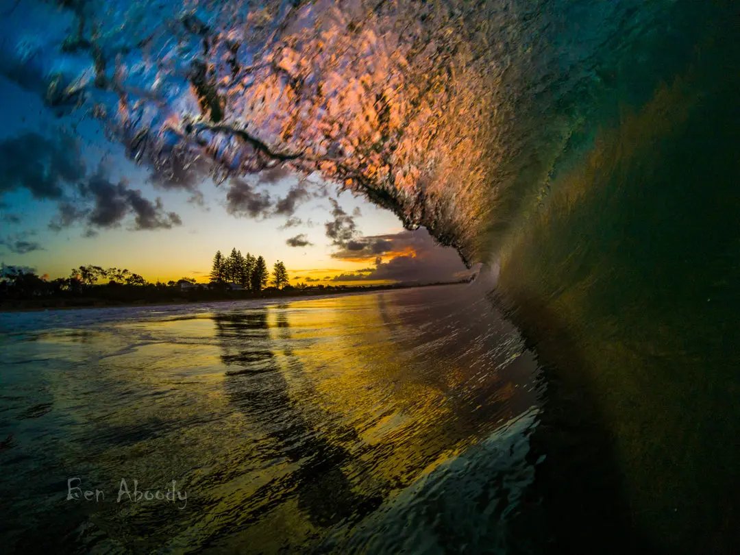 A photograph of a sunset at Byron Bay Beach with a lighthouse in the background, captured by Ben Aboody.